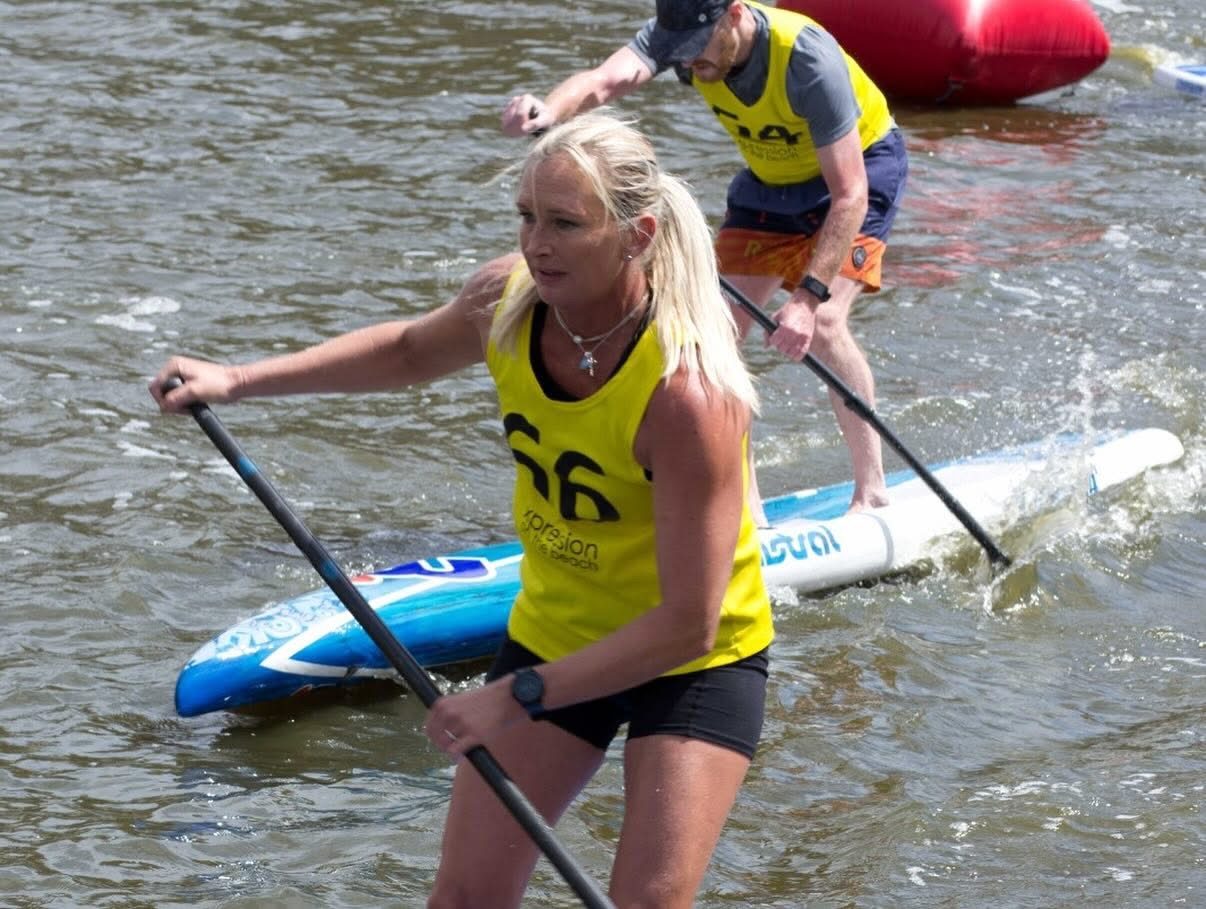 Evette racing on a stand-up paddleboard