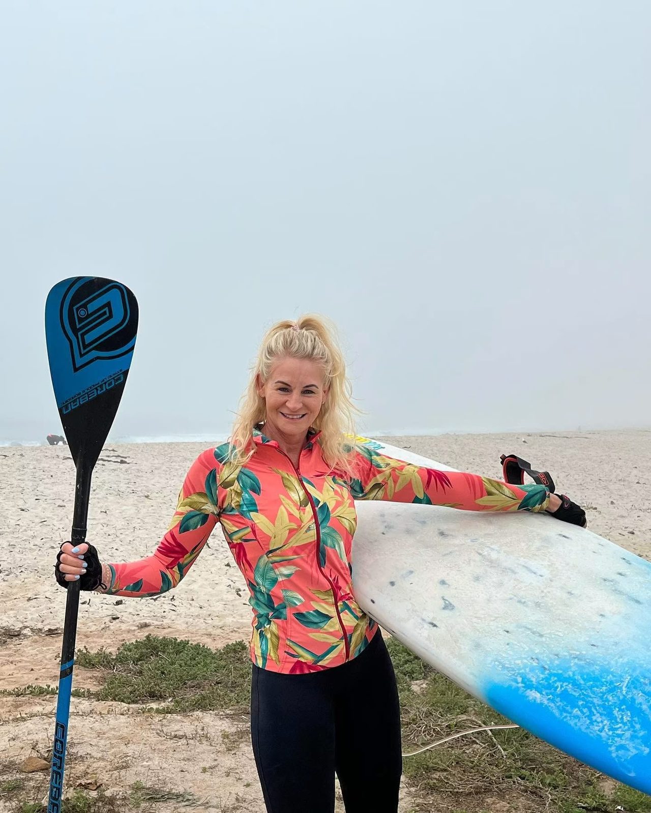 Evette with her paddle and board on the beach