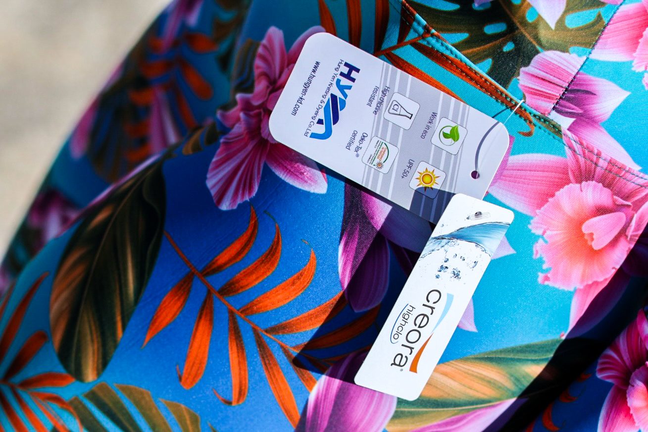 Close up of a bright tropical print fabric with a UPF care label